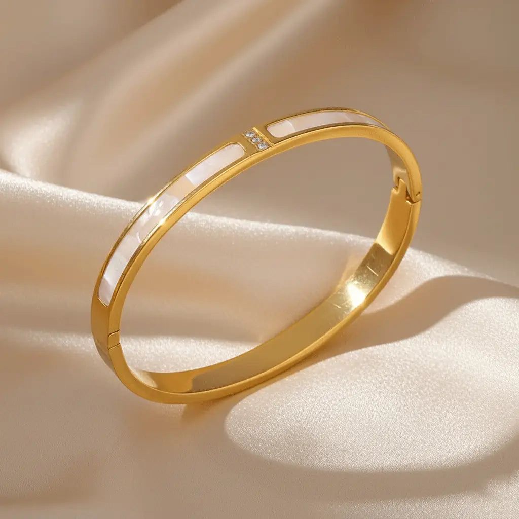 Mother-of-Pearl Gold bracelet featuring elongated mother-of-pearl inlays and a small cluster of crystals, displayed on a satin cloth.