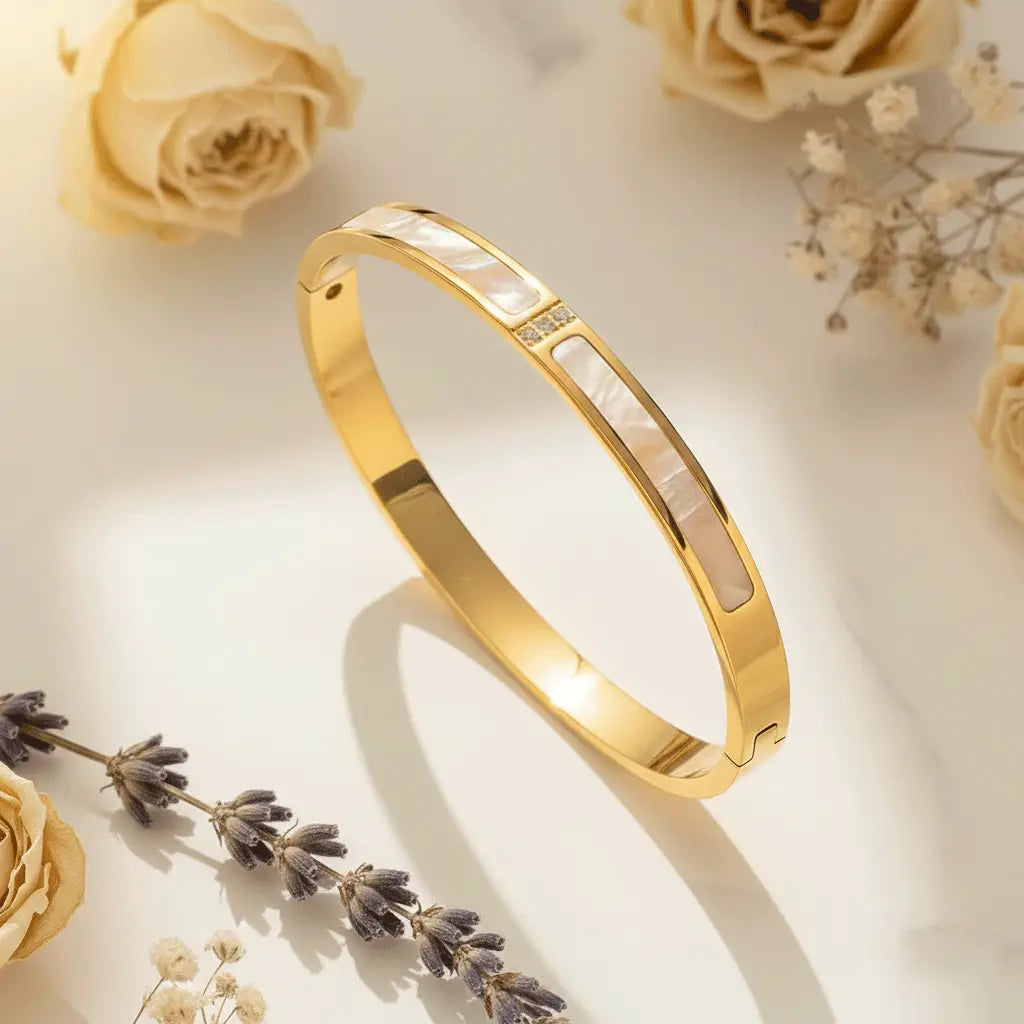 Mother-of-Pearl Gold bracelet featuring elongated mother-of-pearl inlays and a small cluster of crystals, displayed on a softly lit surface with dried roses and lavender sprigs surrounding it.