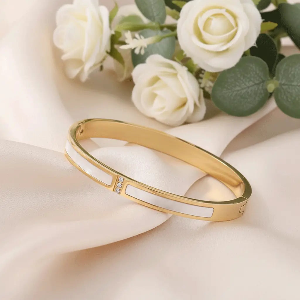 Mother-of-Pearl Gold bracelet featuring elongated mother-of-pearl inlays and a small cluster of crystals, displayed on a softly lit surface with roses