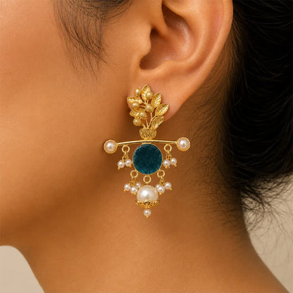 Close-up of Aqua Blossom anti tarnish brass statement earring with teal blue stone, floral brass motif, and pearl embellishments worn by an Indian model.