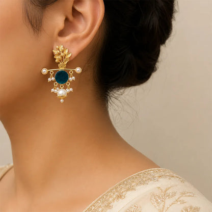Indian model wearing Aqua Blossom anti tarnish brass earrings featuring a teal blue stone, floral gold-toned design, and pearl danglers.