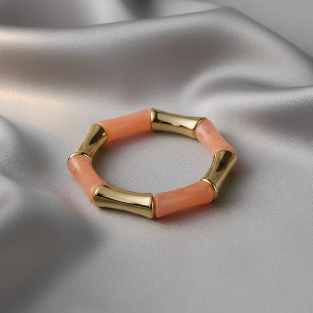 Peach resin and gold bamboo-style bracelet on silver satin fabric.