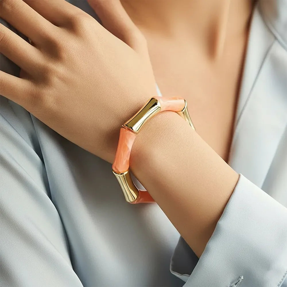 Peach resin and gold bamboo-style bracelet on women's hand.