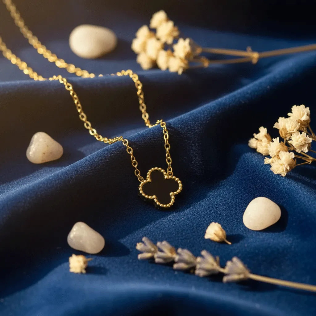 Four-leaf clover pendant featuring a durable anti-tarnish gold trim and reversible black and white design, displayed with lavender and wheat.