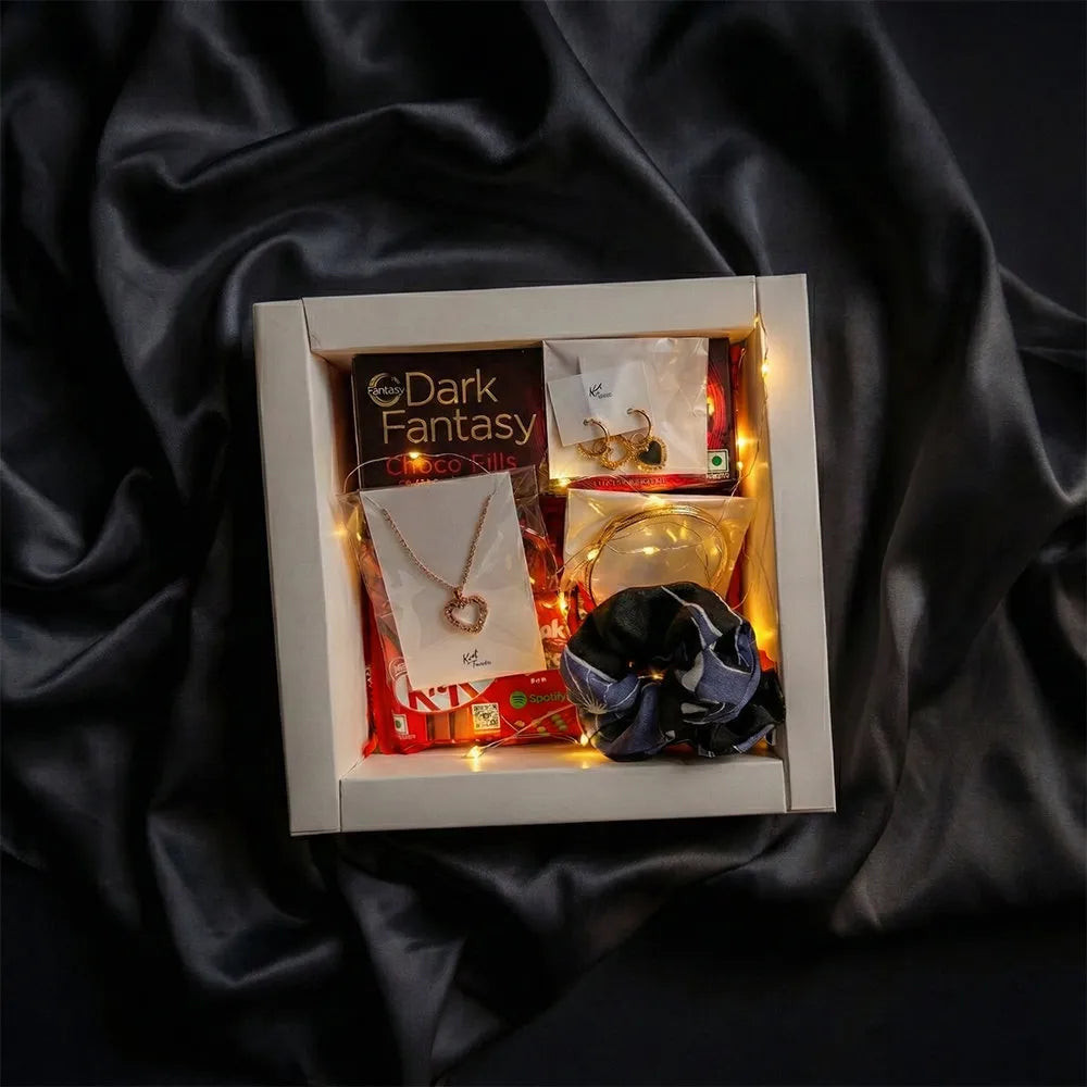 Luxury Valentine jewelry and chocolate hamper with anti-tarnish heart necklace, gold earrings, fairy lights, and premium gift packaging on dark satin background