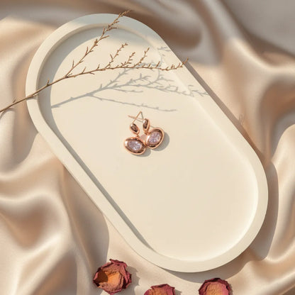 Blush Glow Earrings placed on a cream tray over a satin background with soft natural light.