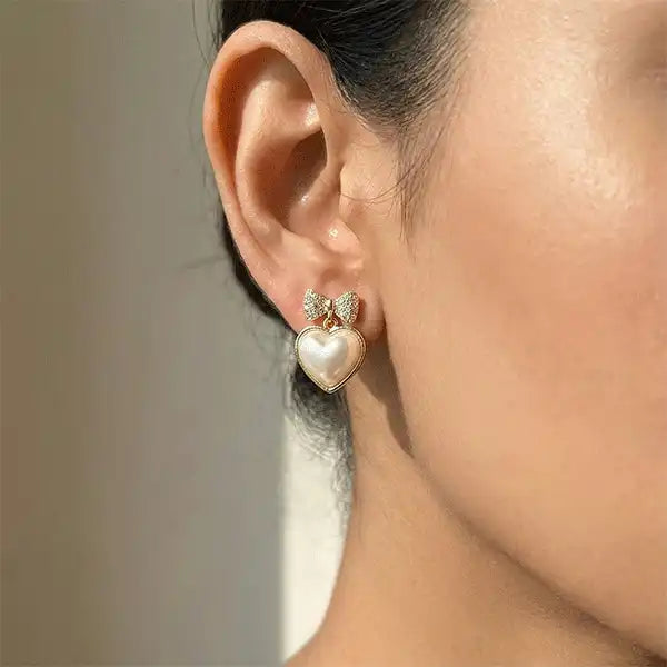 Model wearing bow heart pearl drop earrings in gold finish, anti-tarnish stud earrings close-up ear shot