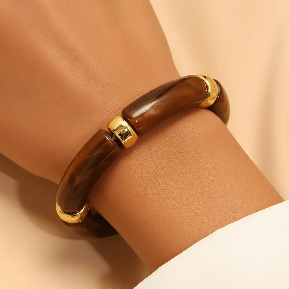 Brown resin bracelet with gold accents on a women's hand.