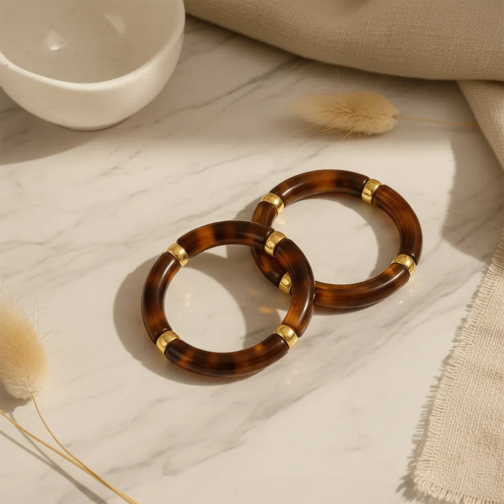 Brown resin bracelet with gold accents displayed on table.