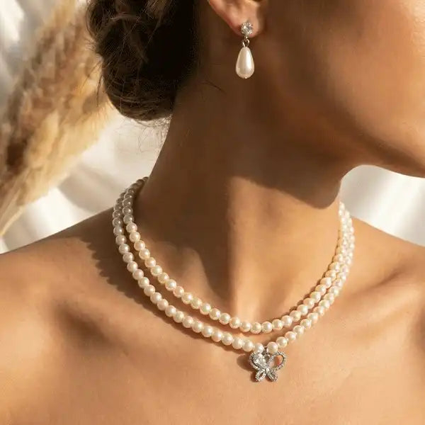 Butterfly pearl necklace worn with matching pearl drop earrings on model