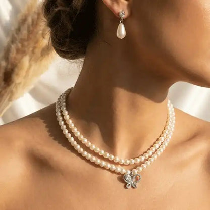 Butterfly pearl necklace worn with matching pearl drop earrings on model