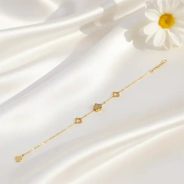 Charm Link Bracelet in gold tone placed on white satin fabric with soft sunlight, minimal floral jewellery design