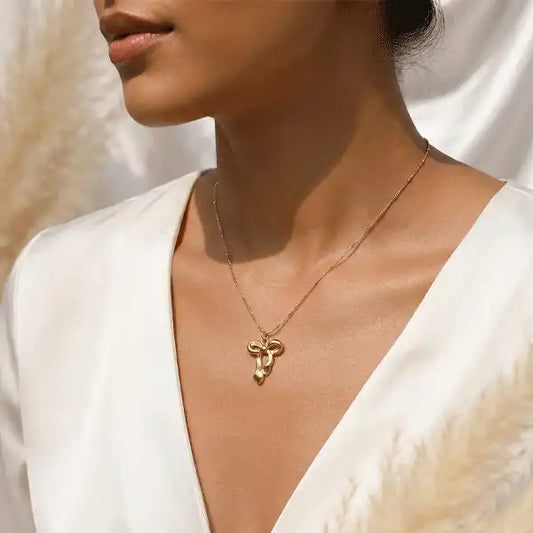 Classic bow drop pendant necklace worn by model, gold finish, minimal elegant jewellery styling