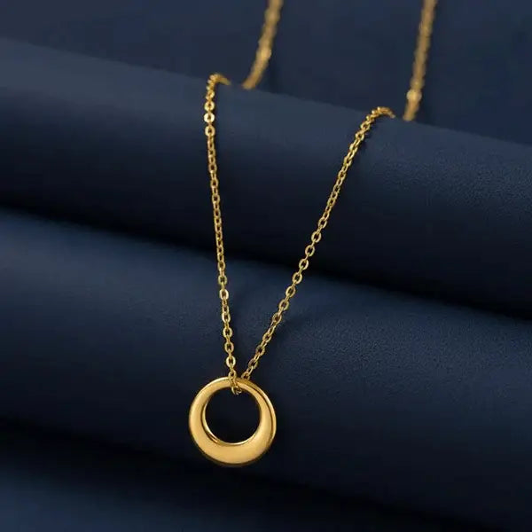 Classic Circle Pendant Necklace – polished gold circular pendant on chain styled on navy blue backdrop