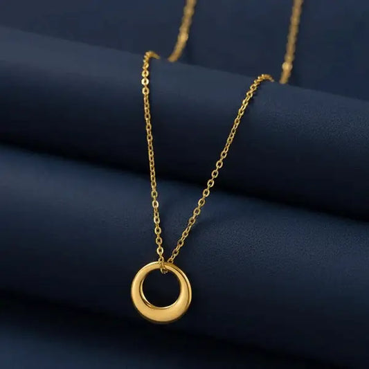 Classic Circle Pendant Necklace – polished gold circular pendant on chain styled on navy blue backdrop