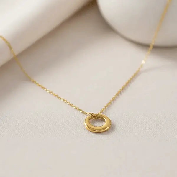 Classic Circle Pendant Necklace – minimal gold round charm on delicate chain displayed on beige background