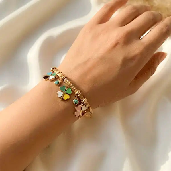 Gold-plated clover charm bangle bracelet with colorful enamel charms, anti-tarnish jewellery on white satin background