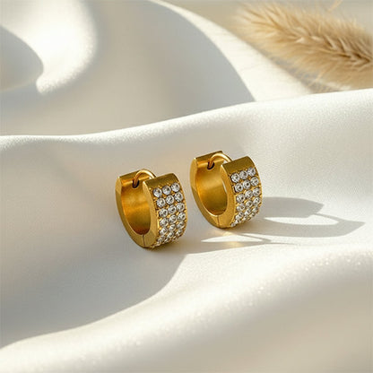 Anti-tarnish gold huggie hoops with crystal detailing displayed on satin background