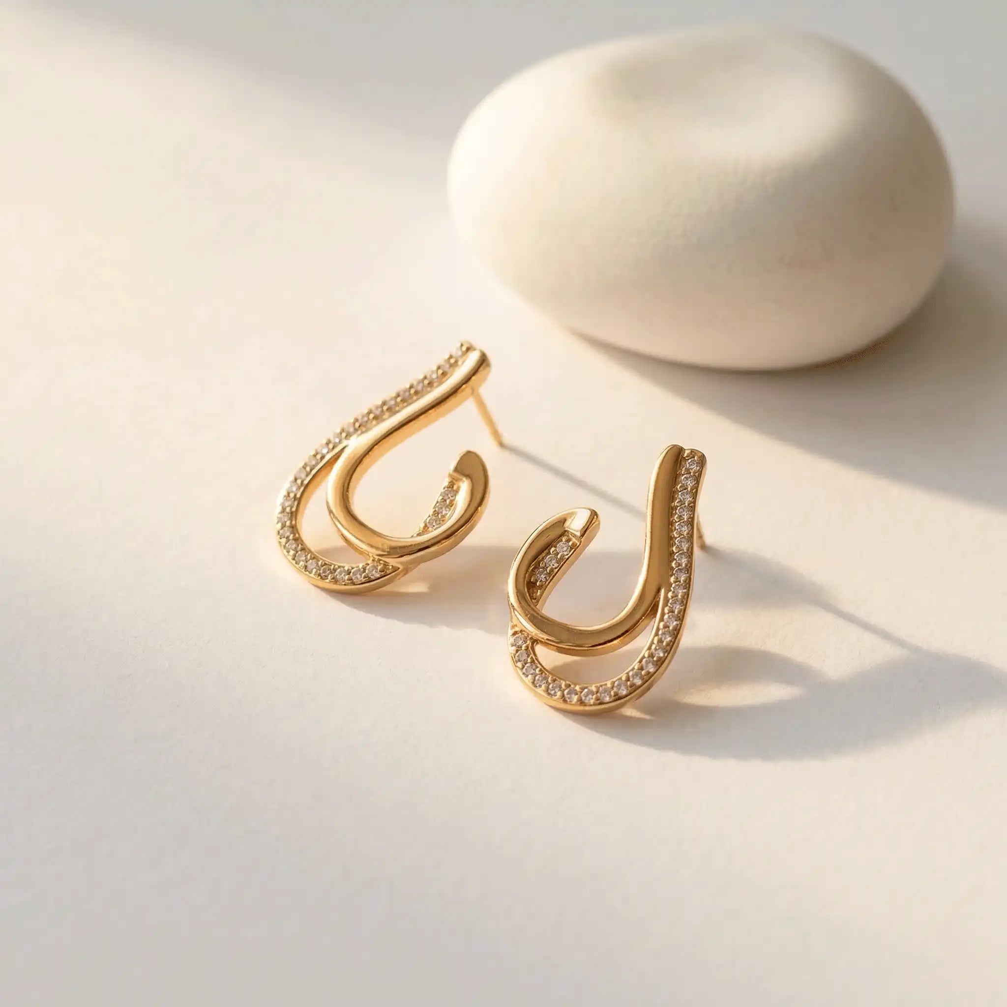 Crystal Curve Drop Earrings with embedded stones on a light background