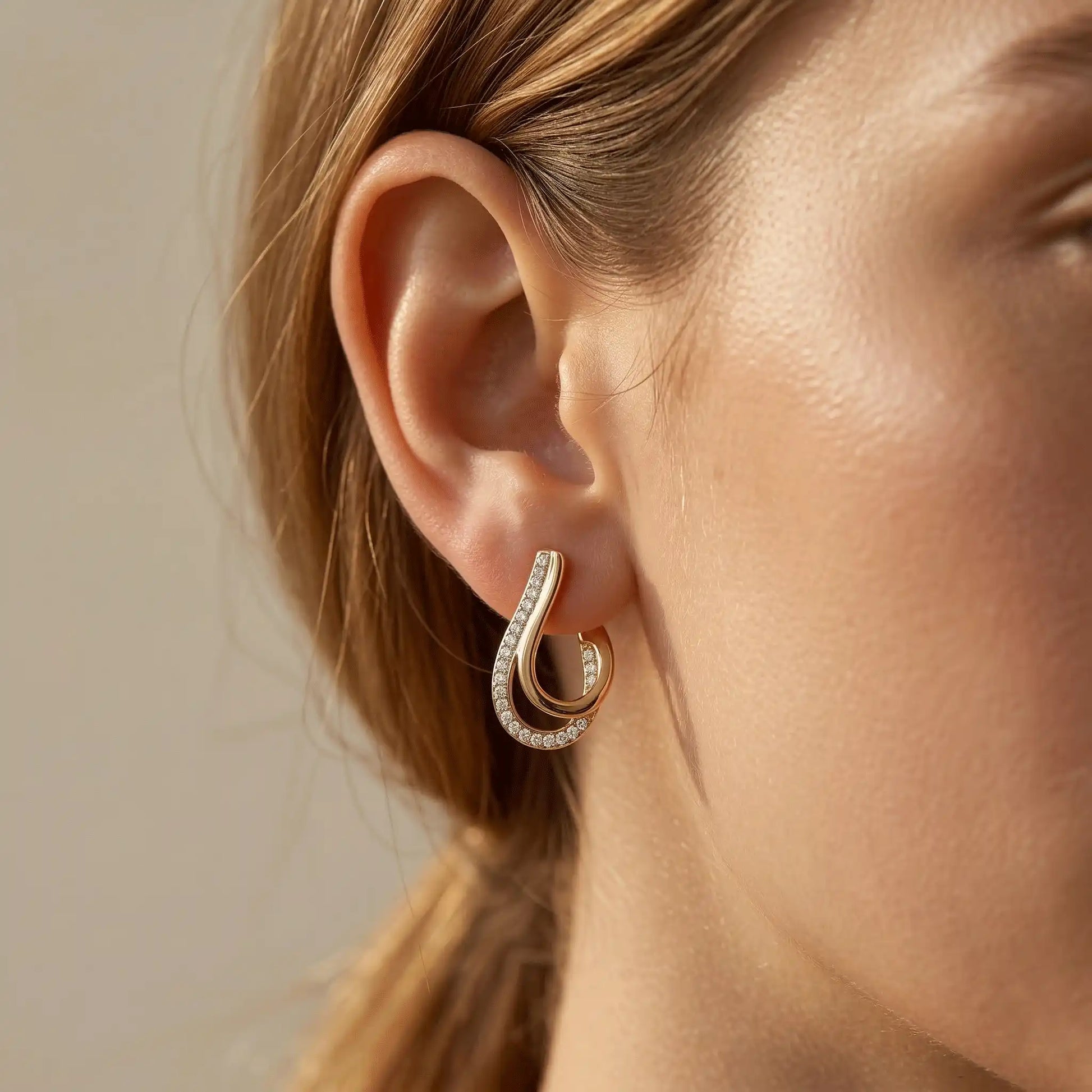 Close-up of a woman wearing Crystal Curve Drop Earrings with clear stones against a neutral background