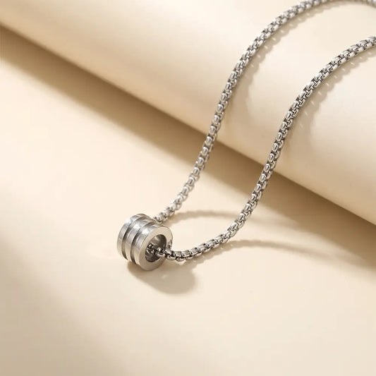 Minimalist silver anti-tarnish cylinder pendant necklace for men displayed on elegant beige studio background from K-A Trends