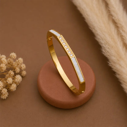 Close-up of Diamond Edge anti tarnish brass bracelet featuring a sleek gold-toned design with white enamel inlays and crystal embellishments.