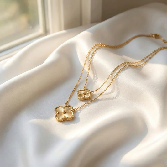 Double gold clover pendant necklace placed on white satin fabric, anti-tarnish gold jewellery with elegant floral design
