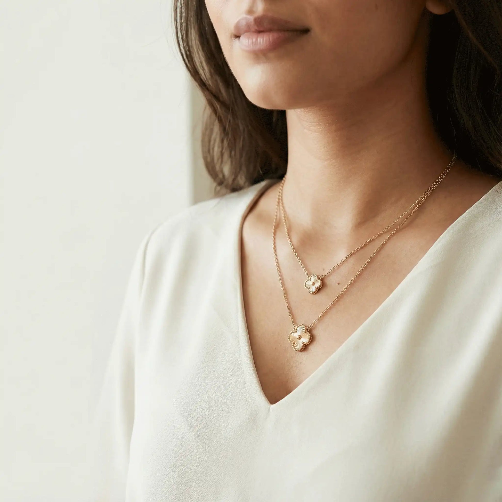 Woman wearing double gold clover pendant necklace, anti-tarnish gold jewellery for everyday and festive wear