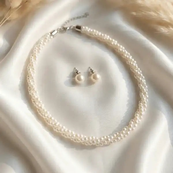 Minimal pearl necklace with matching pearl stud earrings on white satin background