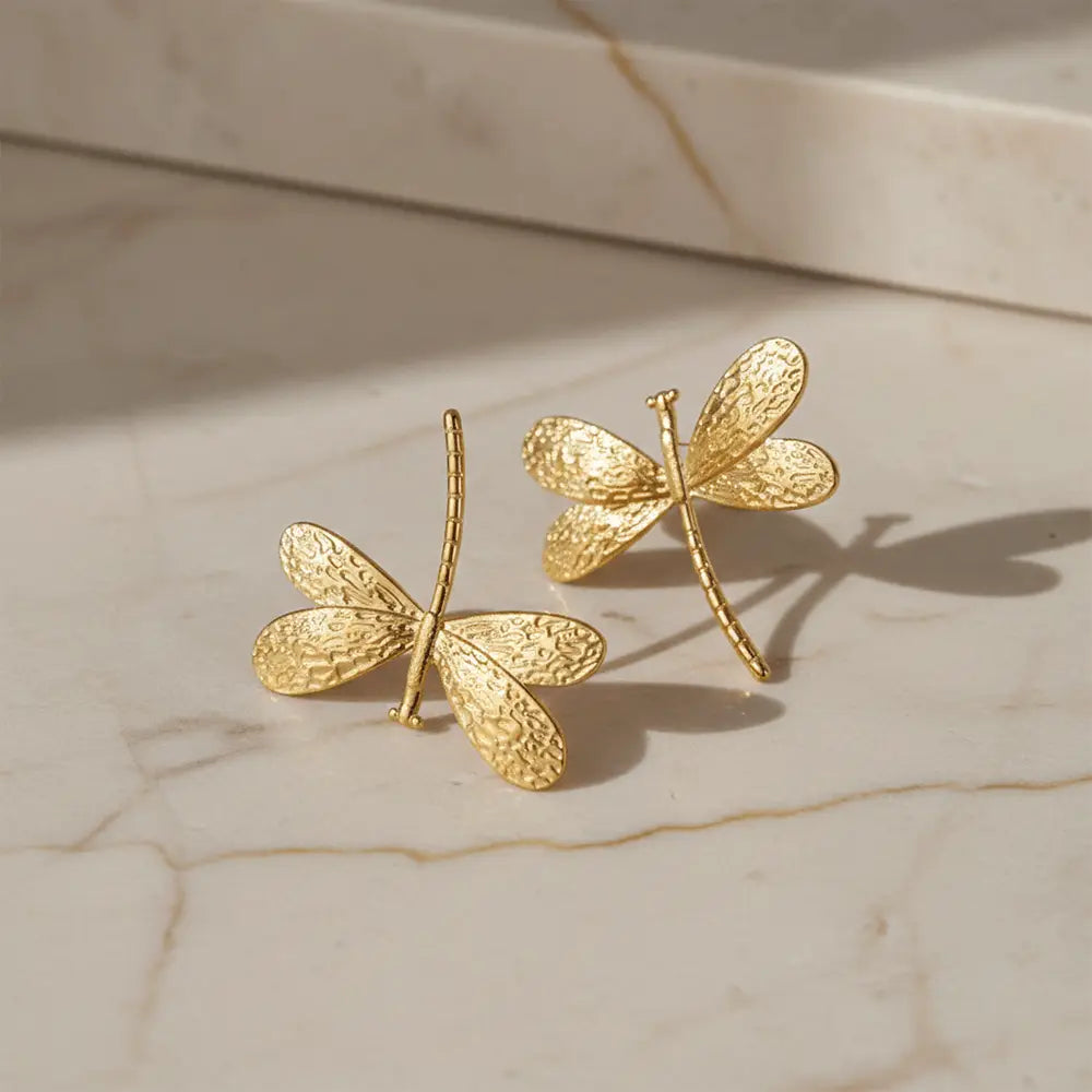 K-A Trends anti tarnish gold dragonfly stud earrings on marble surface with natural sunlight premium jewellery