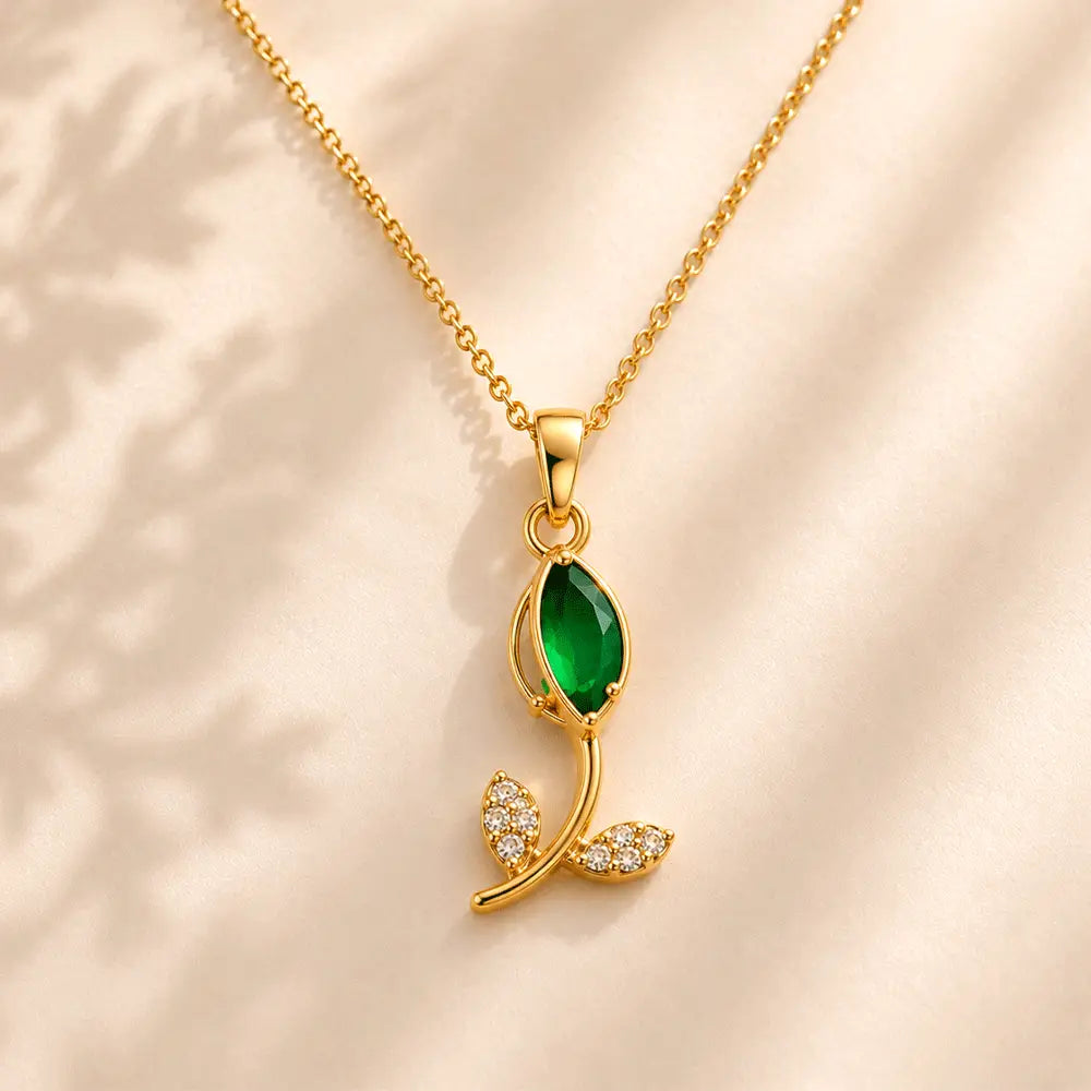 Close-up of Emerald Petal anti tarnish pendant necklace featuring a green marquise gemstone and sparkling crystal leaf accents on a gold-toned chain.