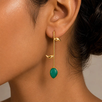 ndian model wearing Emerald Vine anti tarnish brass earrings featuring a green teardrop stone and minimalist gold leaf design.