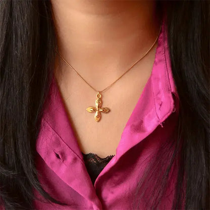 Woman wearing a gold flower pendant necklace with a minimal chain, styled against a magenta outfit.