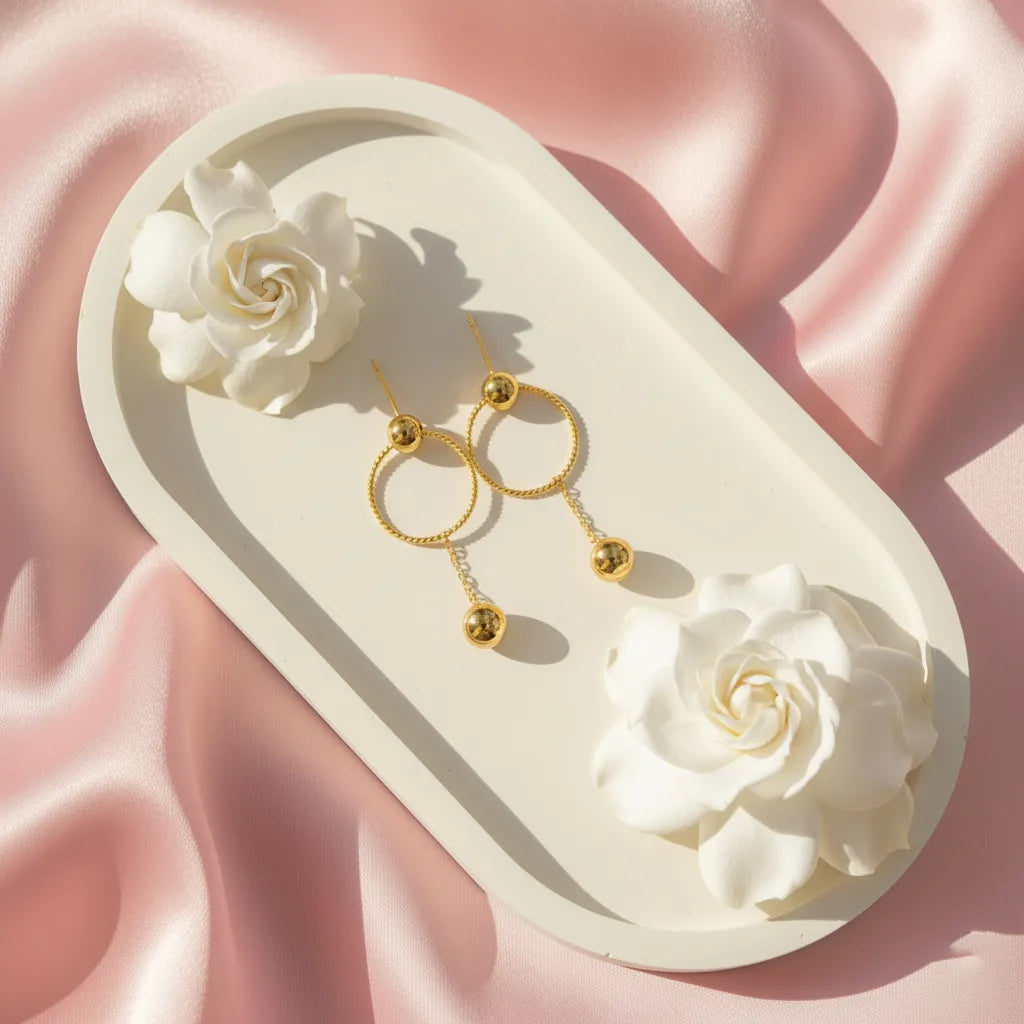 These stylish Golden Ball Hoops feature a twisted circle with a sleek gold ball drop, perfect for any look.