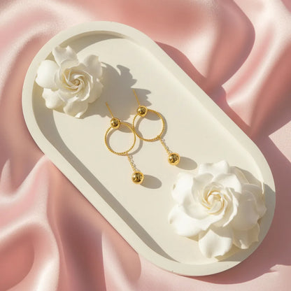 These stylish Golden Ball Hoops feature a twisted circle with a sleek gold ball drop, perfect for any look.