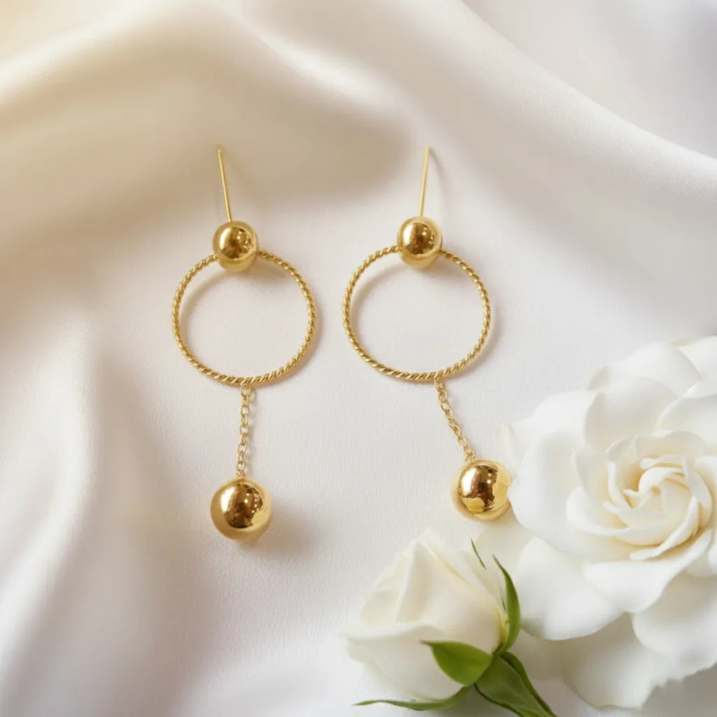 These stylish Golden Ball Hoops feature a twisted circle with a sleek gold ball drop, perfect for any look.