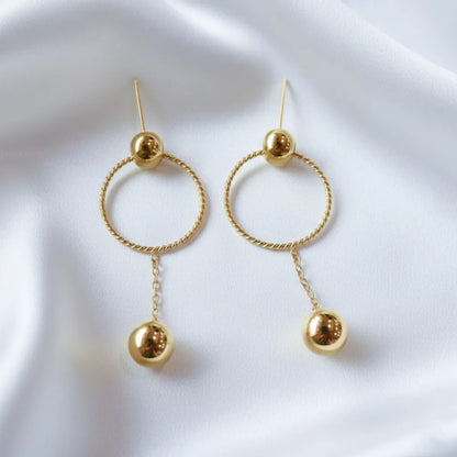 These stylish Golden Ball Hoops feature a twisted circle with a sleek gold ball drop, perfect for any look.
