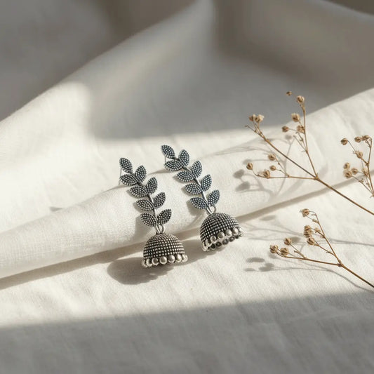 Silver oxidised Pankhuri Jhumka earrings featuring leaf motifs and textured dome hangings.