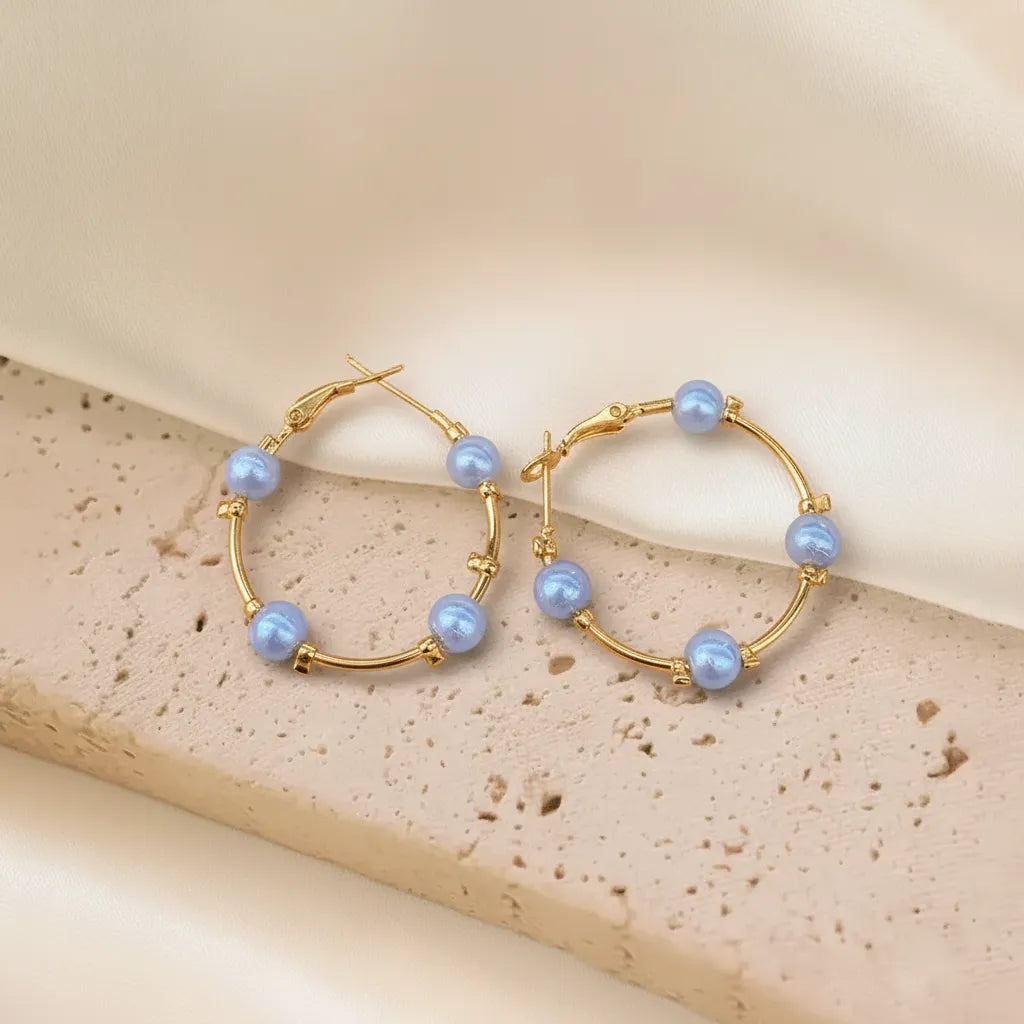 These Pearl Charm Hoops feature a beautiful mix of gold metal and glossy pearls, giving them a stylish look.