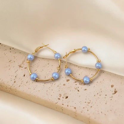 These Pearl Charm Hoops feature a beautiful mix of gold metal and glossy pearls, giving them a stylish look.