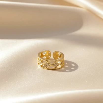 Gold Clover Band Ring featuring openwork clover design and sparkling crystals displayed on soft satin fabric.
