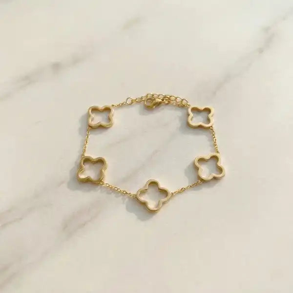 Minimal gold clover charm bracelet anti-tarnish laid flat on marble surface