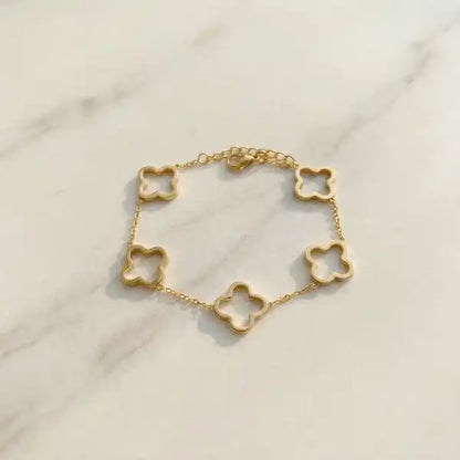 Minimal gold clover charm bracelet anti-tarnish laid flat on marble surface