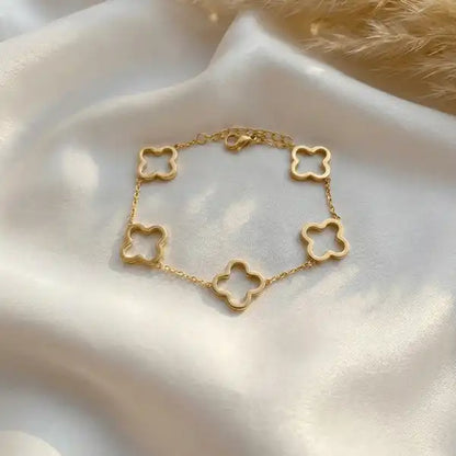 Gold clover charm bracelet anti-tarnish with five clover motifs on white satin background