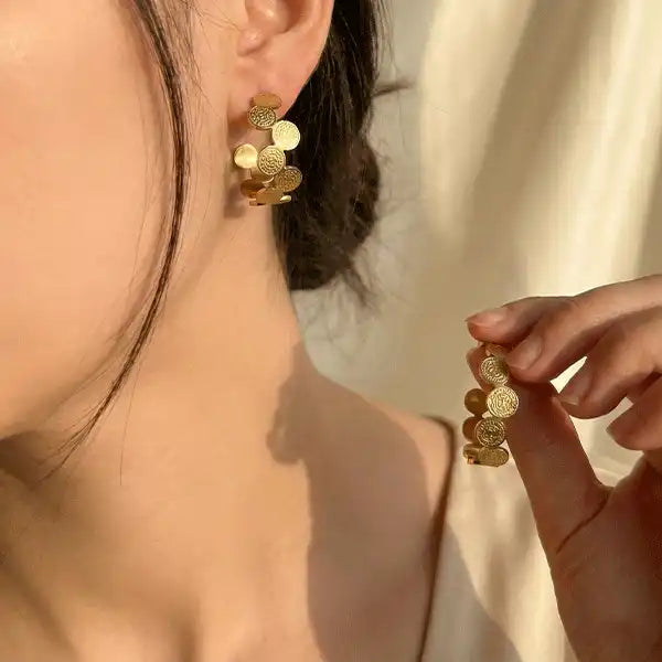Gold Coin Hoops earrings worn by model, textured coin design in anti-tarnish gold with natural sunlight