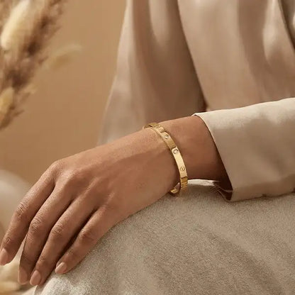 Gold anti-tarnish bangle worn on an Indian female wrist, minimalist luxury bracelet styled with beige outfit in a warm studio setting