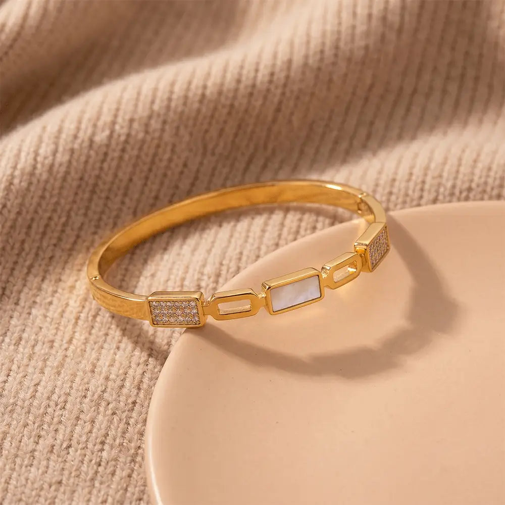Elegant gold anti-tarnish bracelet placed on beige fabric background with crystal detailing and geometric white stone centerpiece by K-A Trends