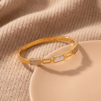 Elegant gold anti-tarnish bracelet placed on beige fabric background with crystal detailing and geometric white stone centerpiece by K-A Trends