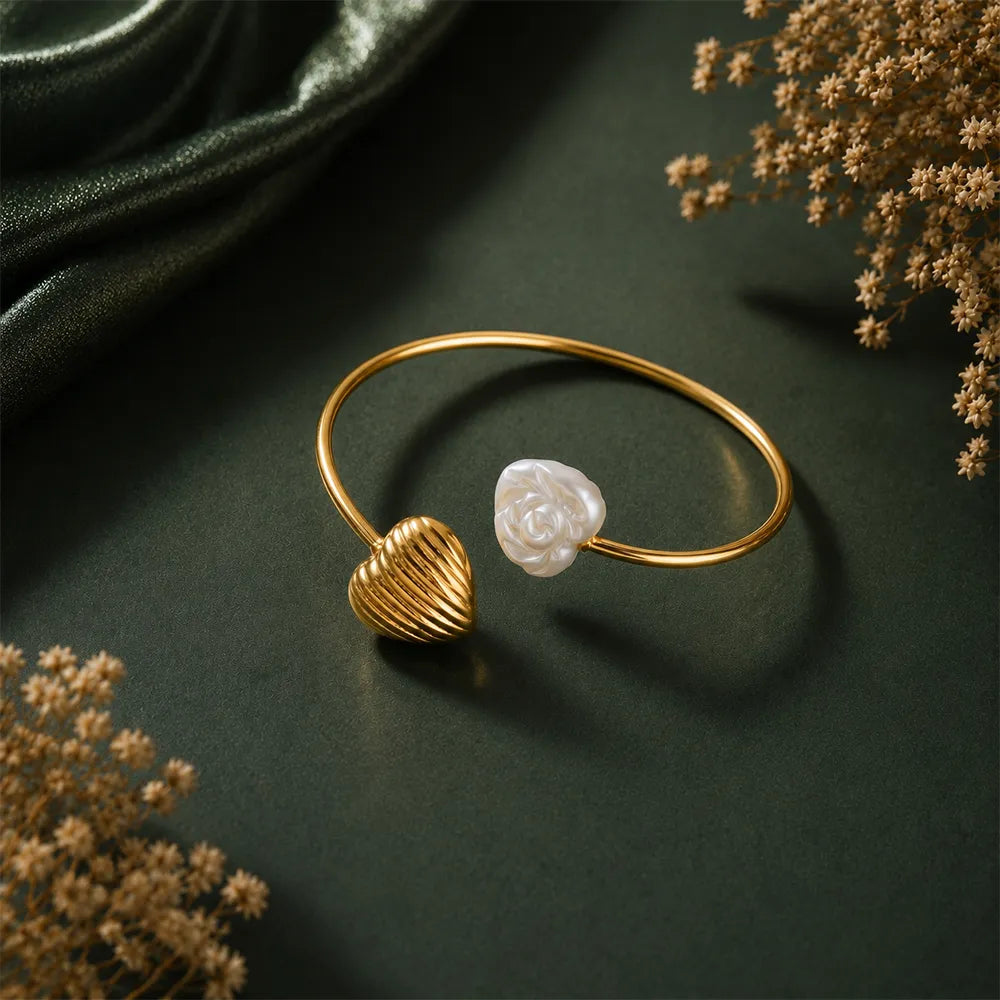 Heart Tide anti tarnish brass bracelet featuring a ribbed gold heart charm and white rose motif on an open cuff design.