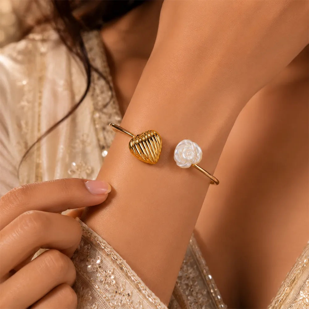 Close-up of Heart Tide anti tarnish brass bracelet featuring an elegant gold heart charm and white floral rose accent on the wrist.